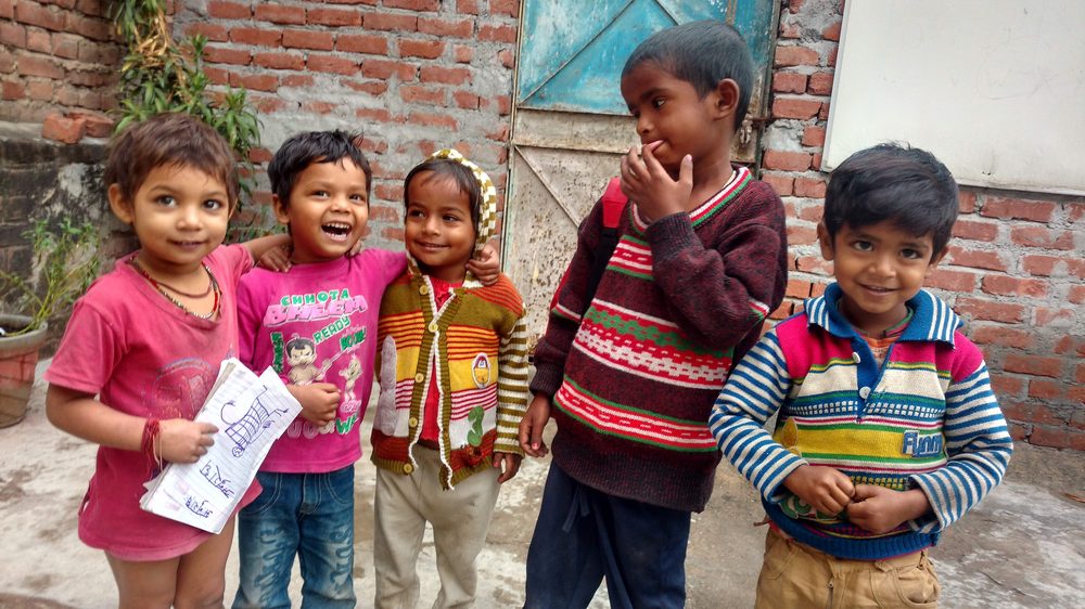 Smiling children outside the learning centre, one holding her notebook
