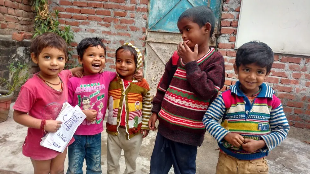 Smiling children outside the learning centre, one holding her notebook