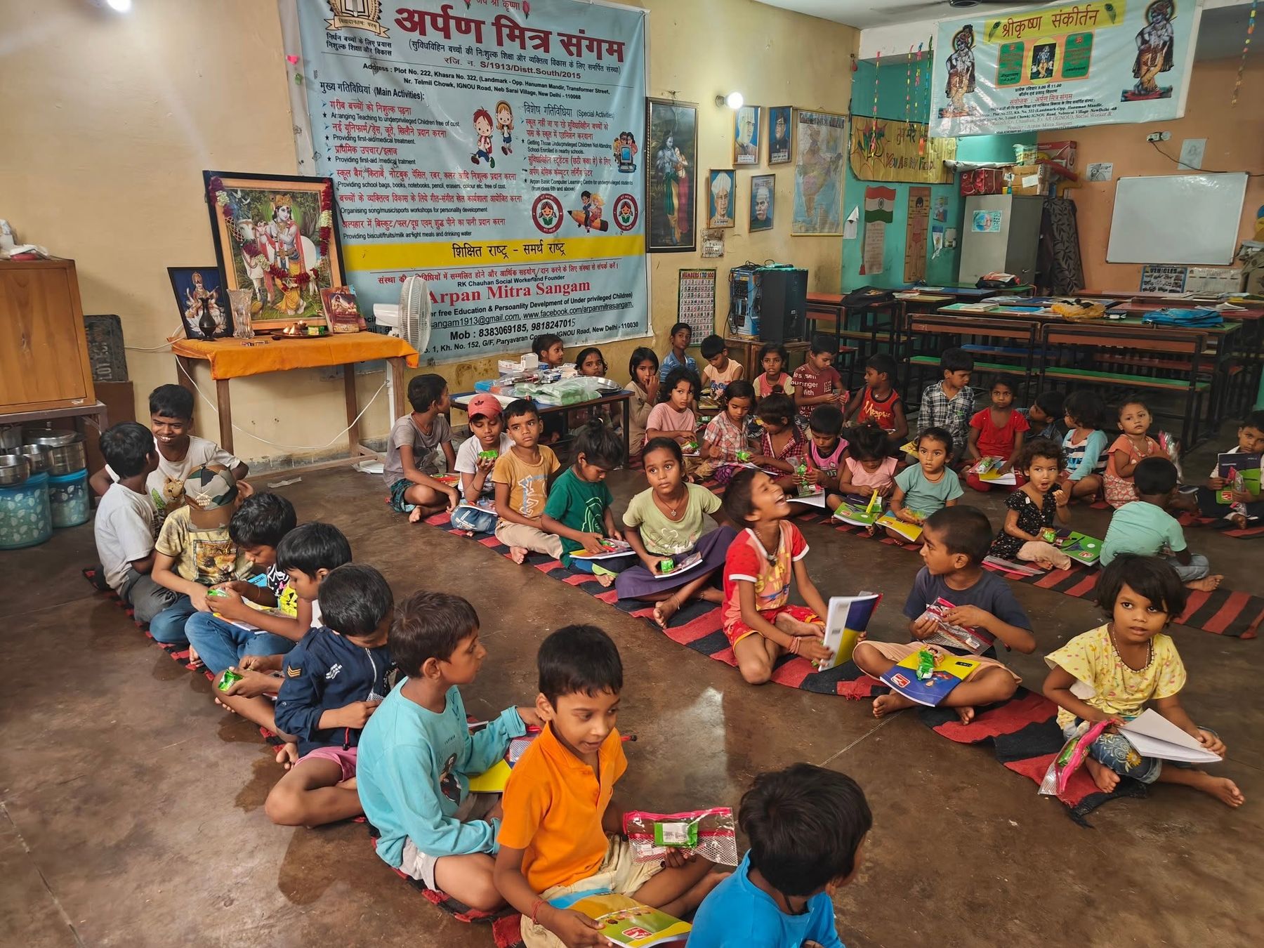 Children sitting with their books on mats at the Arpan Mitra Sangam learning centre