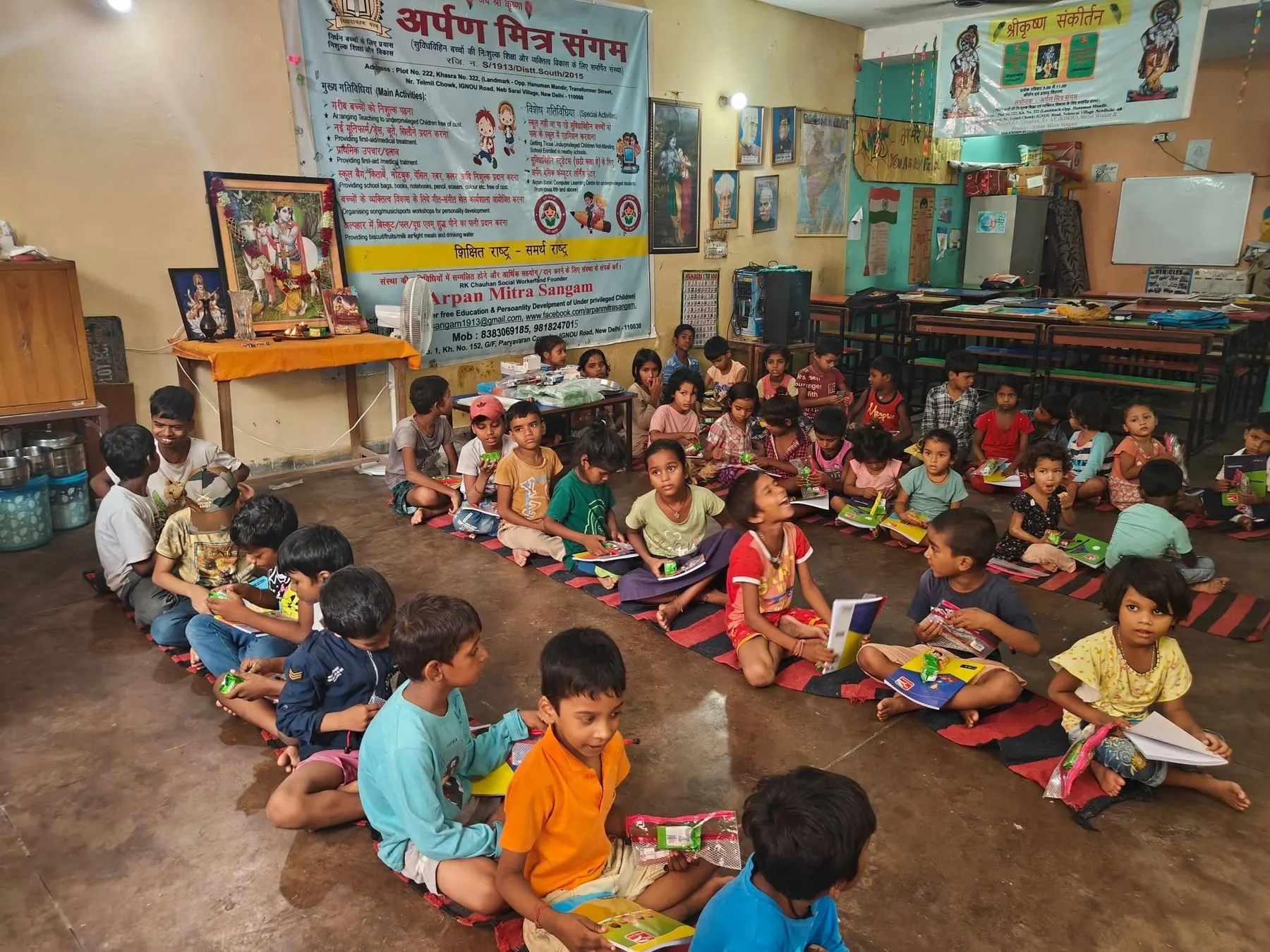 Children sitting with their books on mats at the Arpan Mitra Sangam learning centre