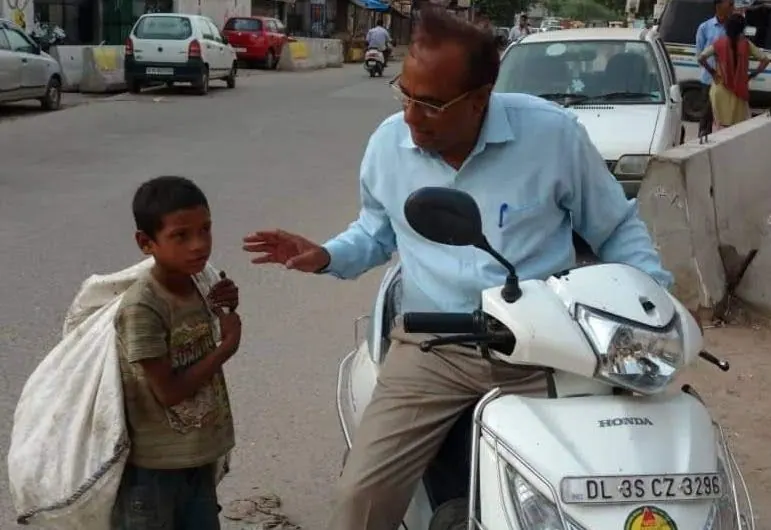 A volunteer talking to a boy collecting scrap on the street