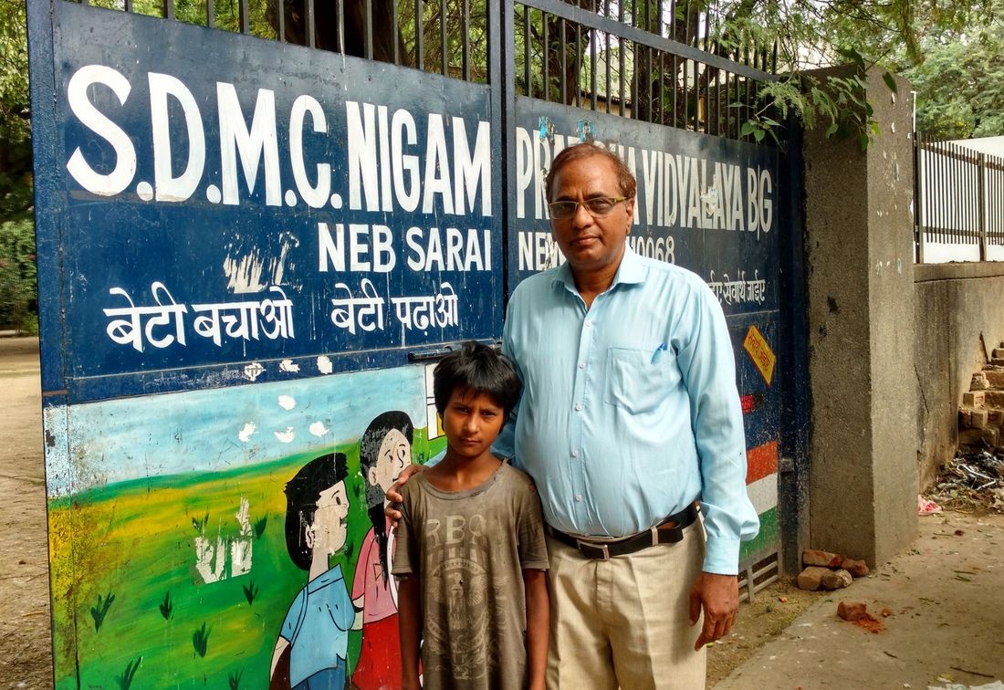 A girl with a volunteer at the gate of the SDMC Nigam Pratibha Vidyalaya school