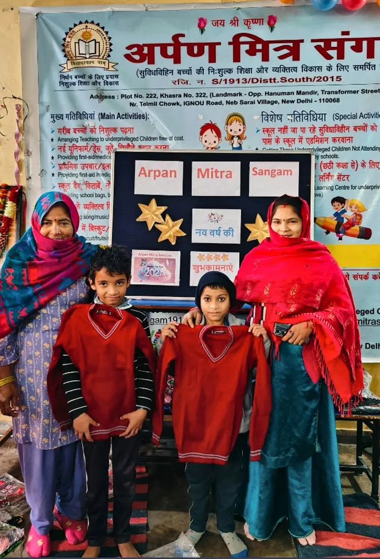 Two children holding their new school sweaters with volunteers